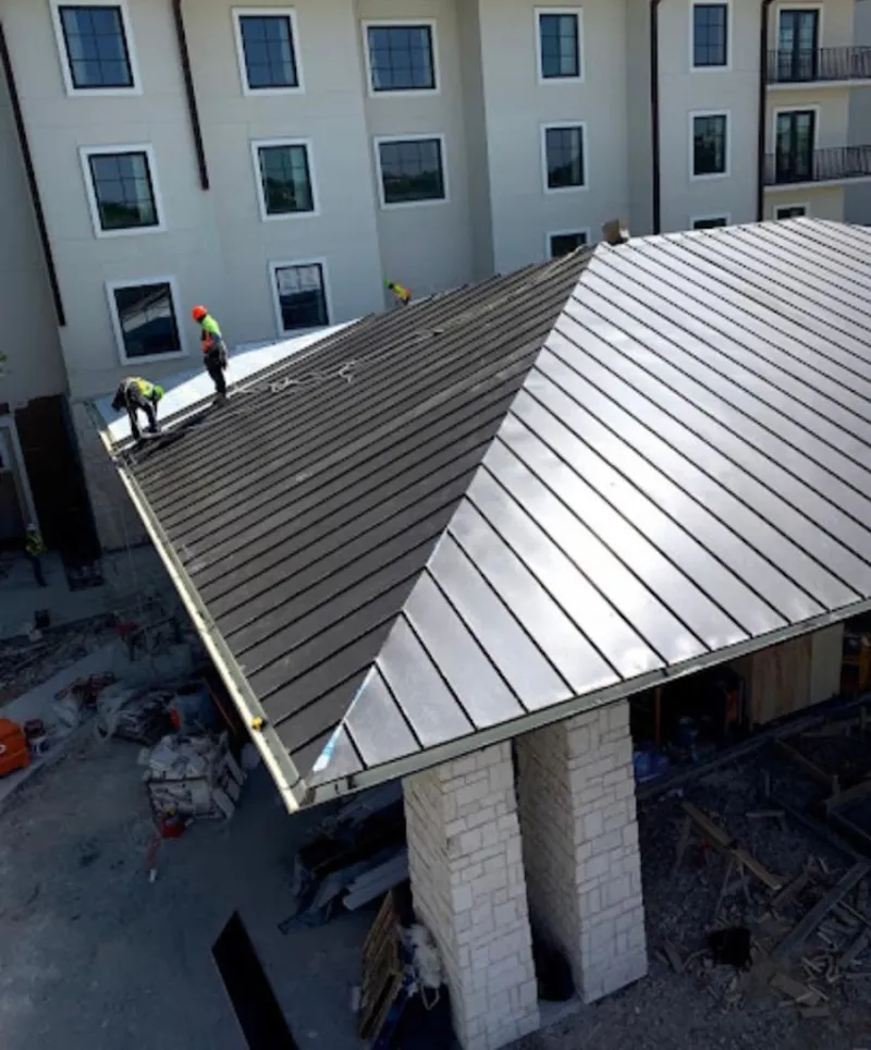 Crew installing standing seam metal roof panels on a commercial project in Kirkwood